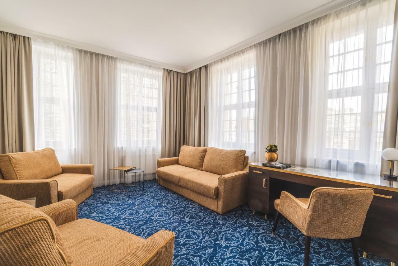 Hotel Suitess Δρέσδη Εξωτερικό φωτογραφία The photo depicts a cozy living room. It features two beige, fabric-covered sofas arranged facing each other, providing a comfortable seating area. Alongside one of the sofas is a small side table. In the corner of the room, there is a wooden desk wi