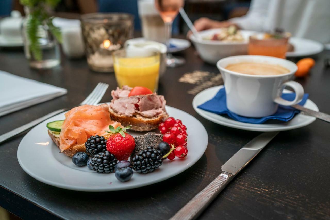 Hotel Suitess Δρέσδη Εξωτερικό φωτογραφία The photo shows a breakfast setting. In the foreground, there's a plate featuring a variety of food items: slices of smoked salmon, a slice of bread topped with meat, and an assortment of fresh berries, including strawberries, blueberries, and blackb