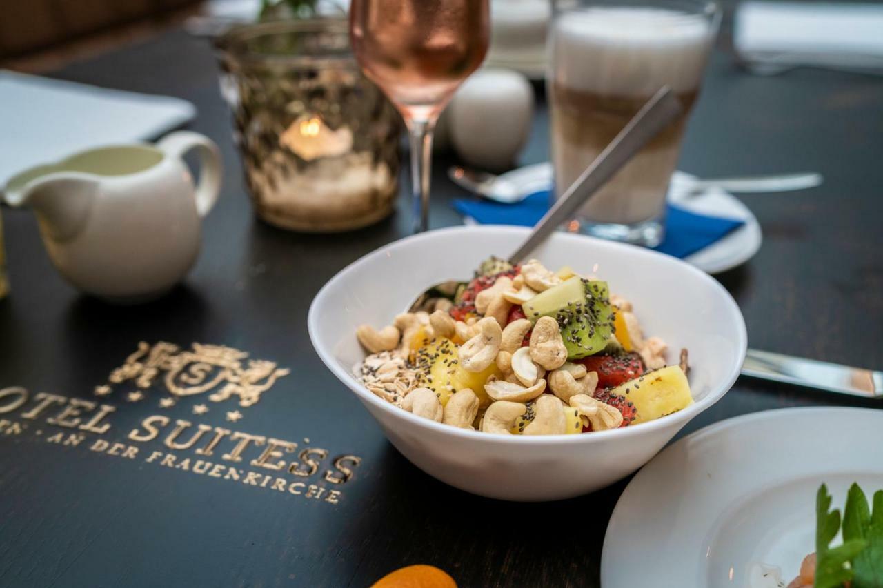 Hotel Suitess Δρέσδη Εξωτερικό φωτογραφία The photo shows a dining setup with a focus on a bowl of salad. The salad contains a mix of ingredients, including pieces of fruit and vegetables, possibly topped with nuts. In the background, there are drinks, including a glass of rosé and a cup of 