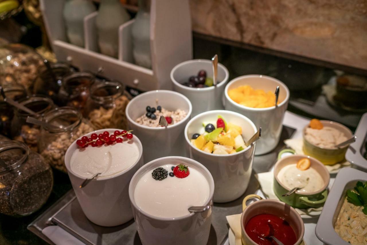 Hotel Suitess Δρέσδη Εξωτερικό φωτογραφία The photo shows a selection of dessert items arranged in small containers. There are several bowls filled with different treats, including:

1. A bowl with white yogurt topped with red berries.
2. Another bowl of yogurt with blackberries and possibly