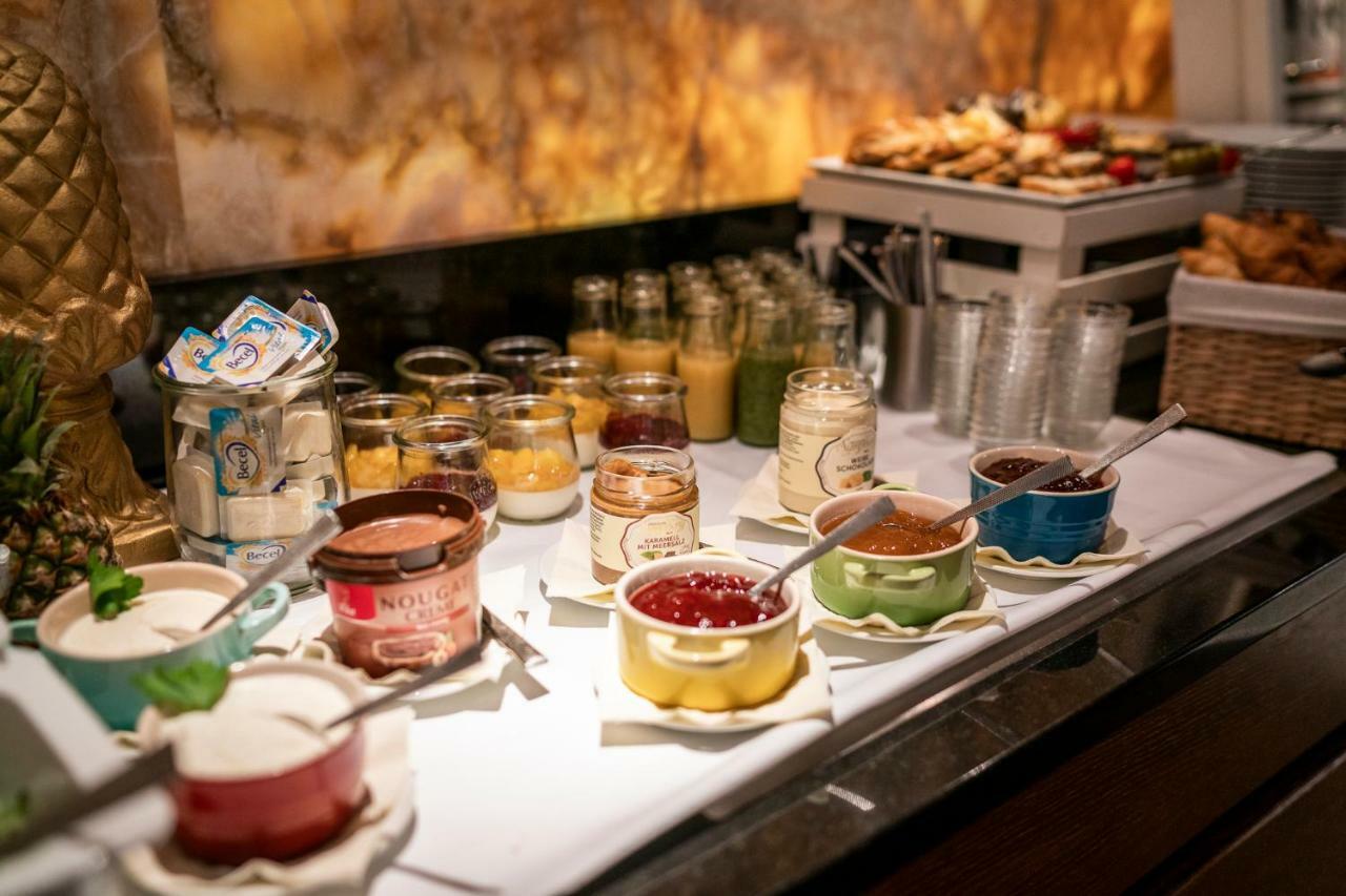 Hotel Suitess Δρέσδη Εξωτερικό φωτογραφία The photo shows a buffet-style breakfast spread. There are various containers and jars filled with different types of jams, spreads, and possibly yogurt. The jars are arranged neatly, with some lids open and spoons placed inside for serving. In the b